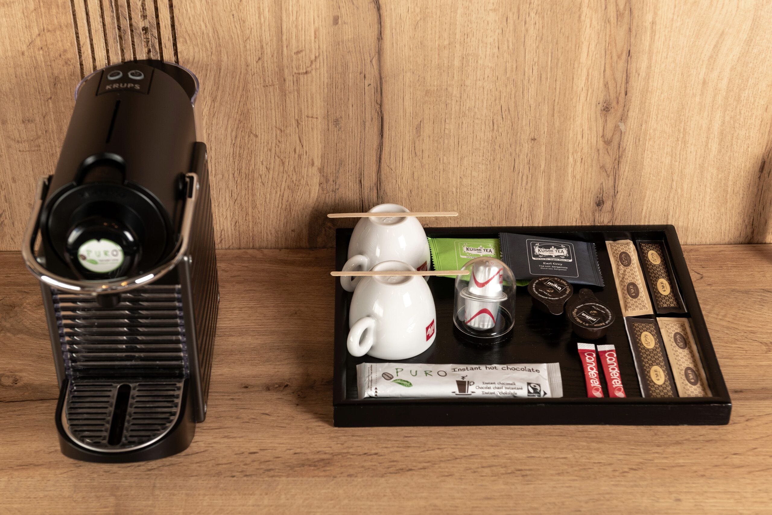 Eine Kaffeemaschine, ein Teekessel und ein Tablett mit Tee und Schokoladenriegeln.