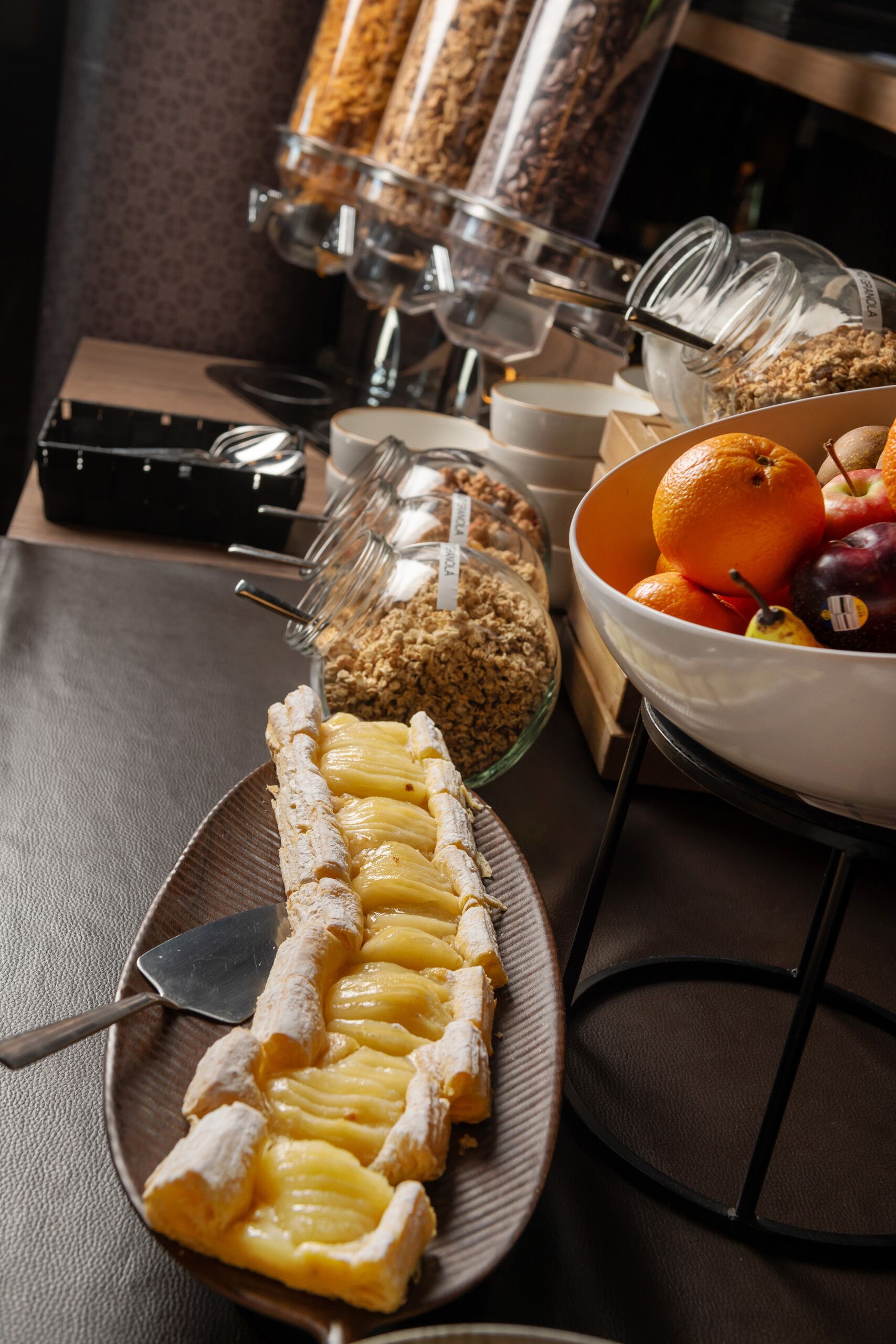 Een ontbijtbuffet met diverse gerechten, waaronder een bord gebak, een schaal fruit en een koffieapparaat.
