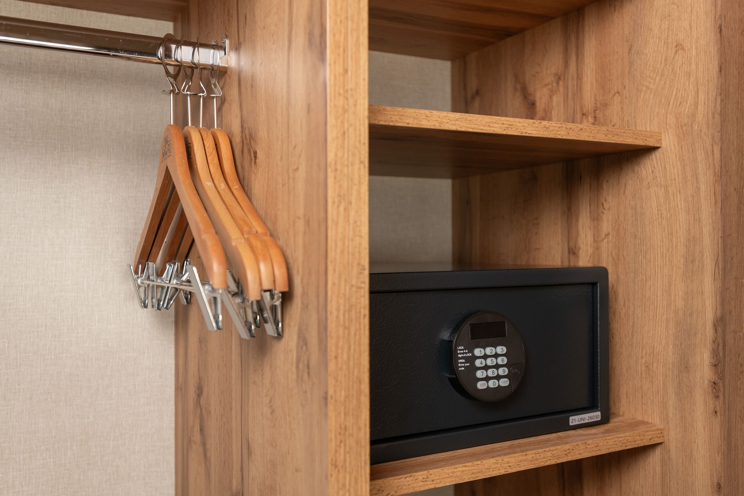 A wooden cabinet with a black safe and a metal coat rack with wooden hooks.