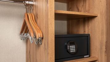 A wooden cabinet with a black safe and a metal coat rack with wooden hooks.