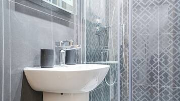 A bathroom with a white sink, a mirror, and a shower enclosure.