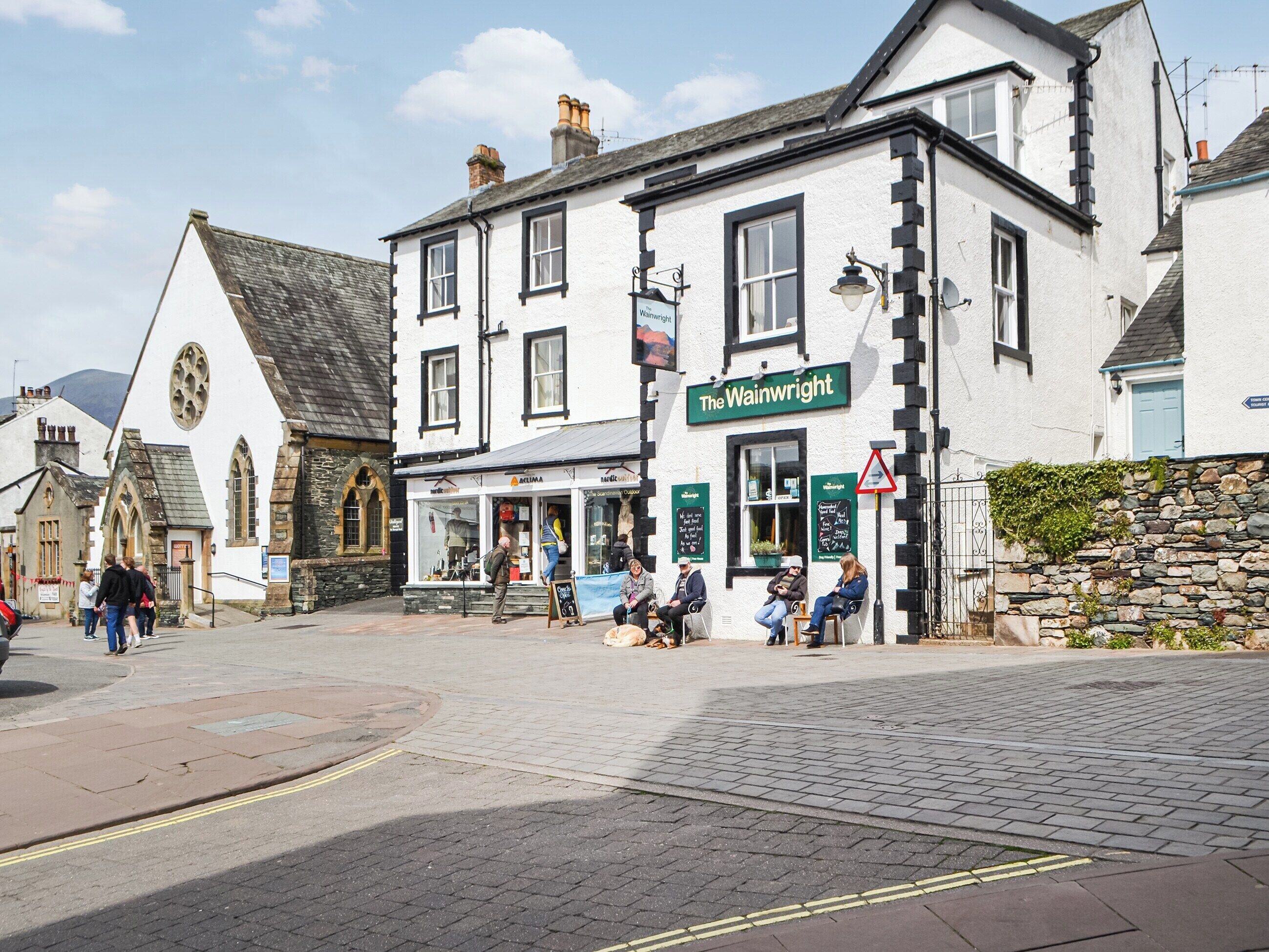 A traditional pub named 'The Wainwright' with a stone facade, multiple windows, and a signboard.