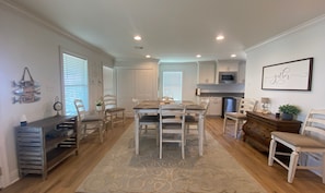 A spacious living room with a dining area, a kitchen, and a hallway.