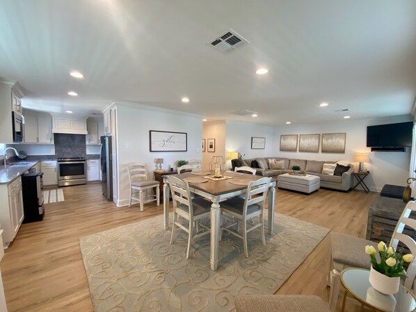 A modern living space with a dining area, kitchen, and seating area.