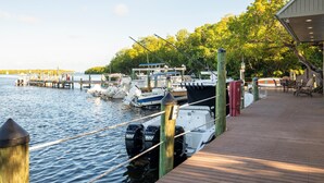 A dock with boats, a wooden pier, and a covered seating area with tables and chairs. - Poolside Cottage #412 (Key West)