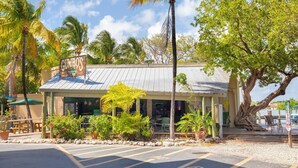 A building with a sign reading "CUMBO'S KEY WEST" and a parking area in front. - Poolside Cottage #412 (Key West)