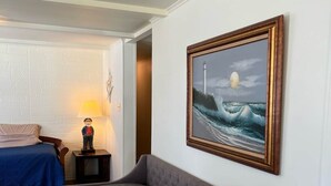 Ein Zimmer mit einem Bett, einem Sofa, einer Lampe und einem gerahmten Bild eines Leuchtturms an der Wand.