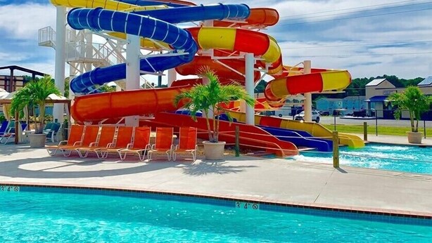 A water park with multiple water slides in blue, red, and yellow, a pool, and lounge chairs.