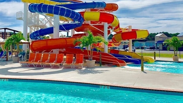 A water park with multiple water slides in blue, red, and yellow, a pool, and lounge chairs.