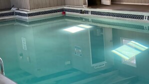 A swimming pool with a tiled edge, a window, and a sign indicating a no swimming zone. - Shipwreck Villa (Chincoteague)
