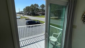 A balcony with a view of a street and parked cars. - Shipwreck Villa (Chincoteague)