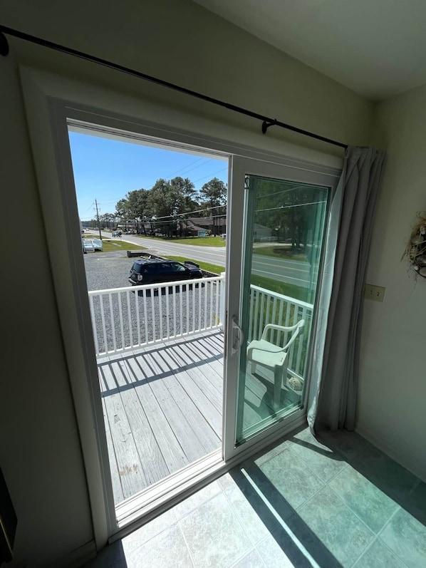 A balcony with a view of a street and parked cars. - Shipwreck Villa (Chincoteague)