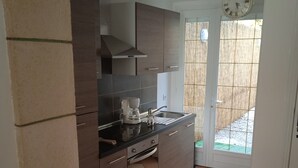 A kitchen with dark wooden cabinets, a coffee maker, and a window with a view of a garden. - Charming Mersoise house 7 minutes walk from the beach with private covered parking (Mers-les-Bains)