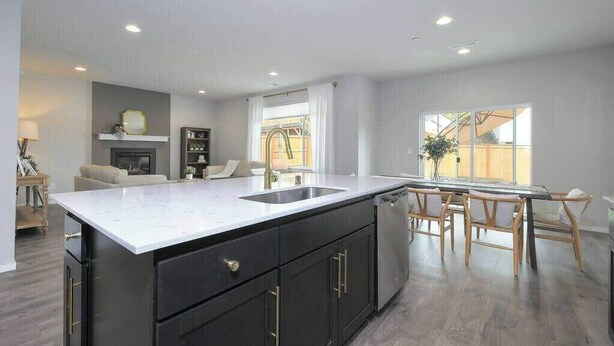 Een moderne keuken met een groot eiland, inbouwapparatuur en een eethoek met houten stoelen.