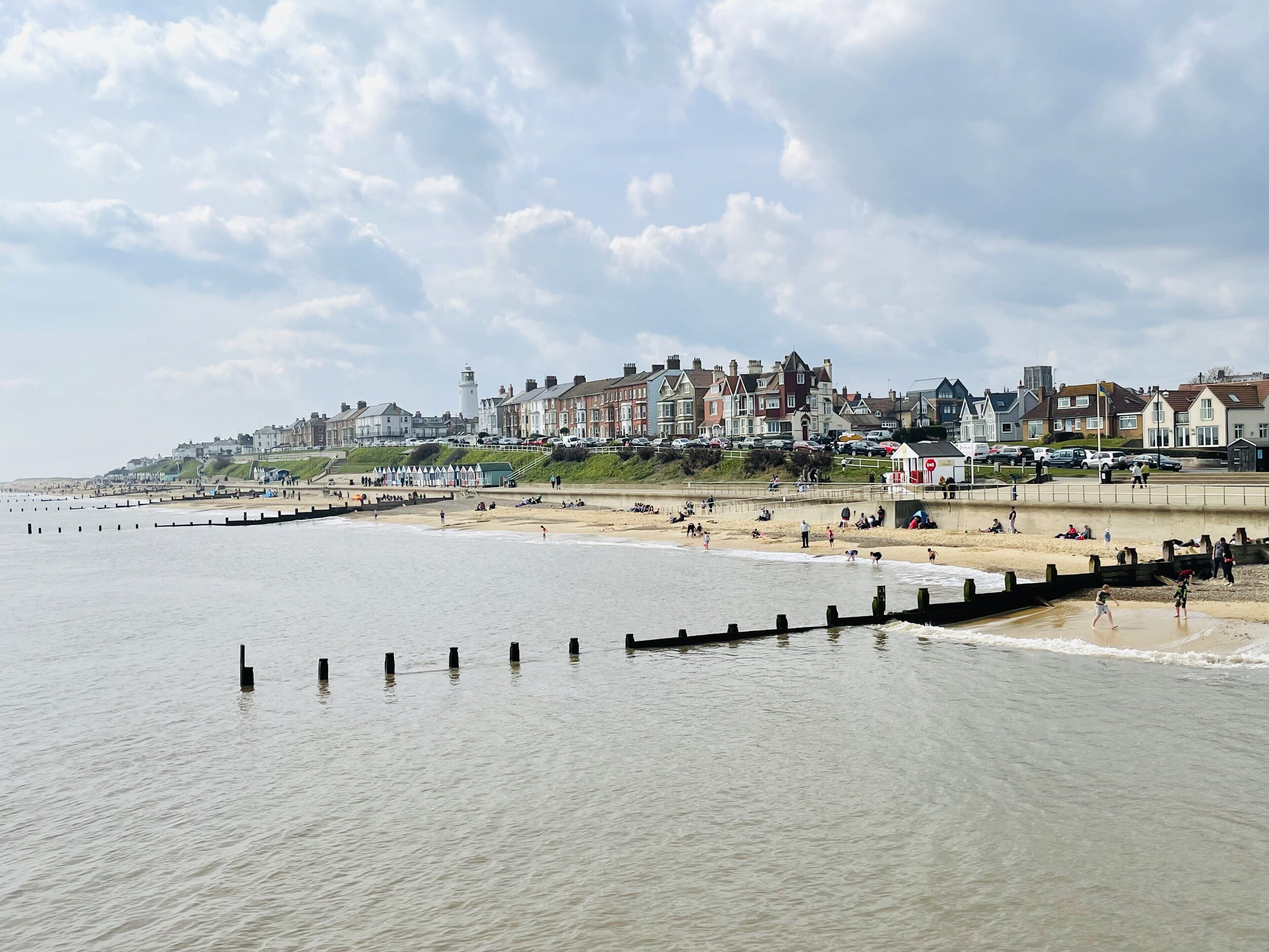 A coastal town with a sandy beach, a promenade, and residential buildings.