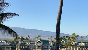 A resort with a pool, palm trees, and a view of mountains.