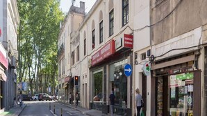 Una vista de carrer amb un restaurant anomenat "Tropical Burger" i una farmàcia.