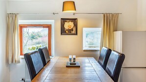 Un comedor con una mesa de madera, sillas de cuero negro, una lámpara colgante y una imagen de una orquídea enmarcada en la pared.
