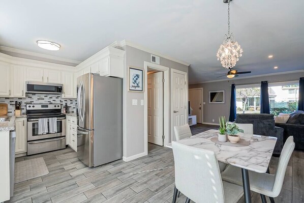A modern kitchen with stainless steel appliances, a dining area with a marble table, and a ceiling fan. - Camelback Condo I Steps from Old Town Scottsdale (Scottsdale)