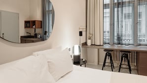 A hotel room with a large bed, a desk with a chair, a mirror, a window with curtains, and a radiator. - TG Hotel Apartments Budapest (Budapest)