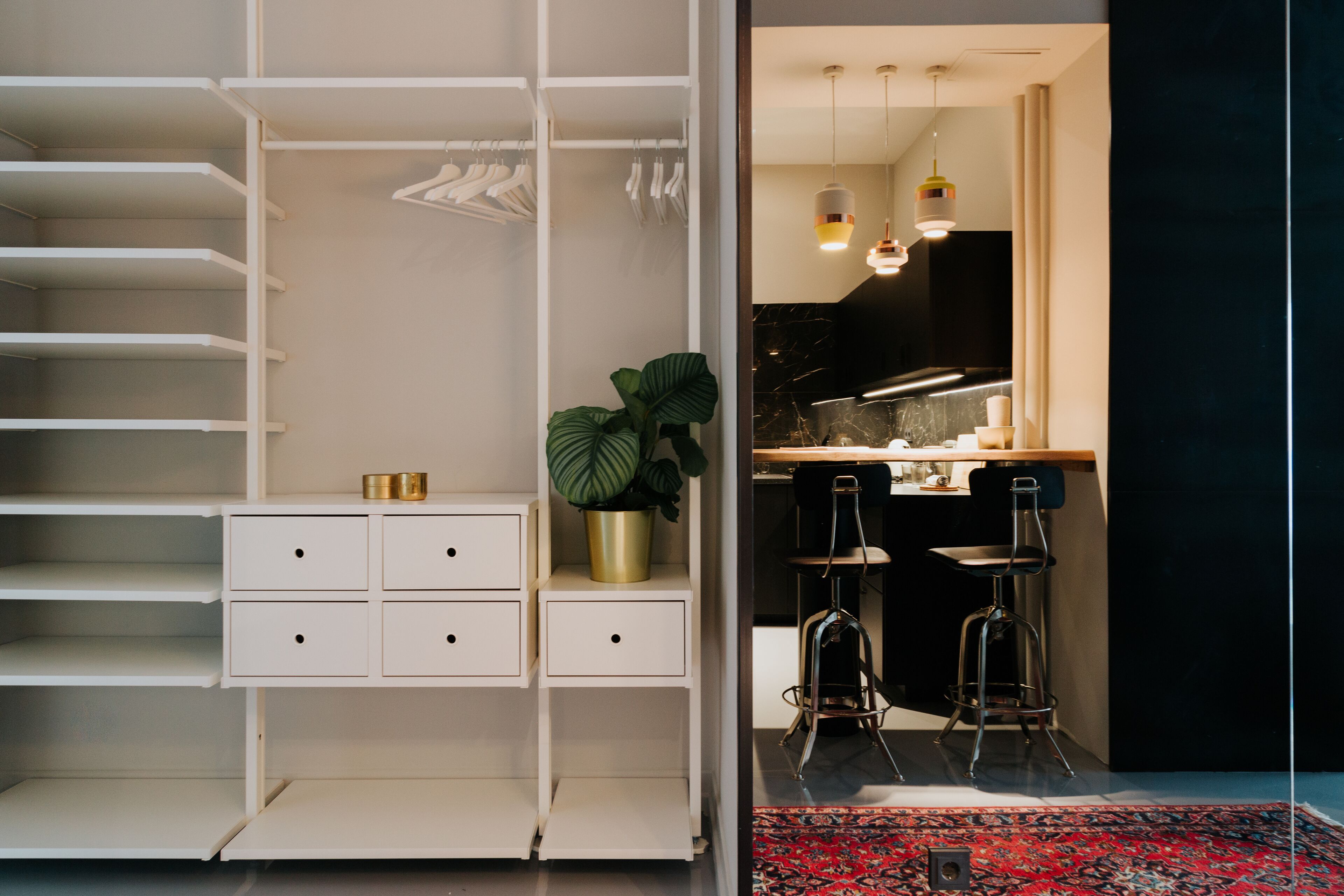 A modern interior with a walk-in closet, a kitchen area, and a bar stool.
