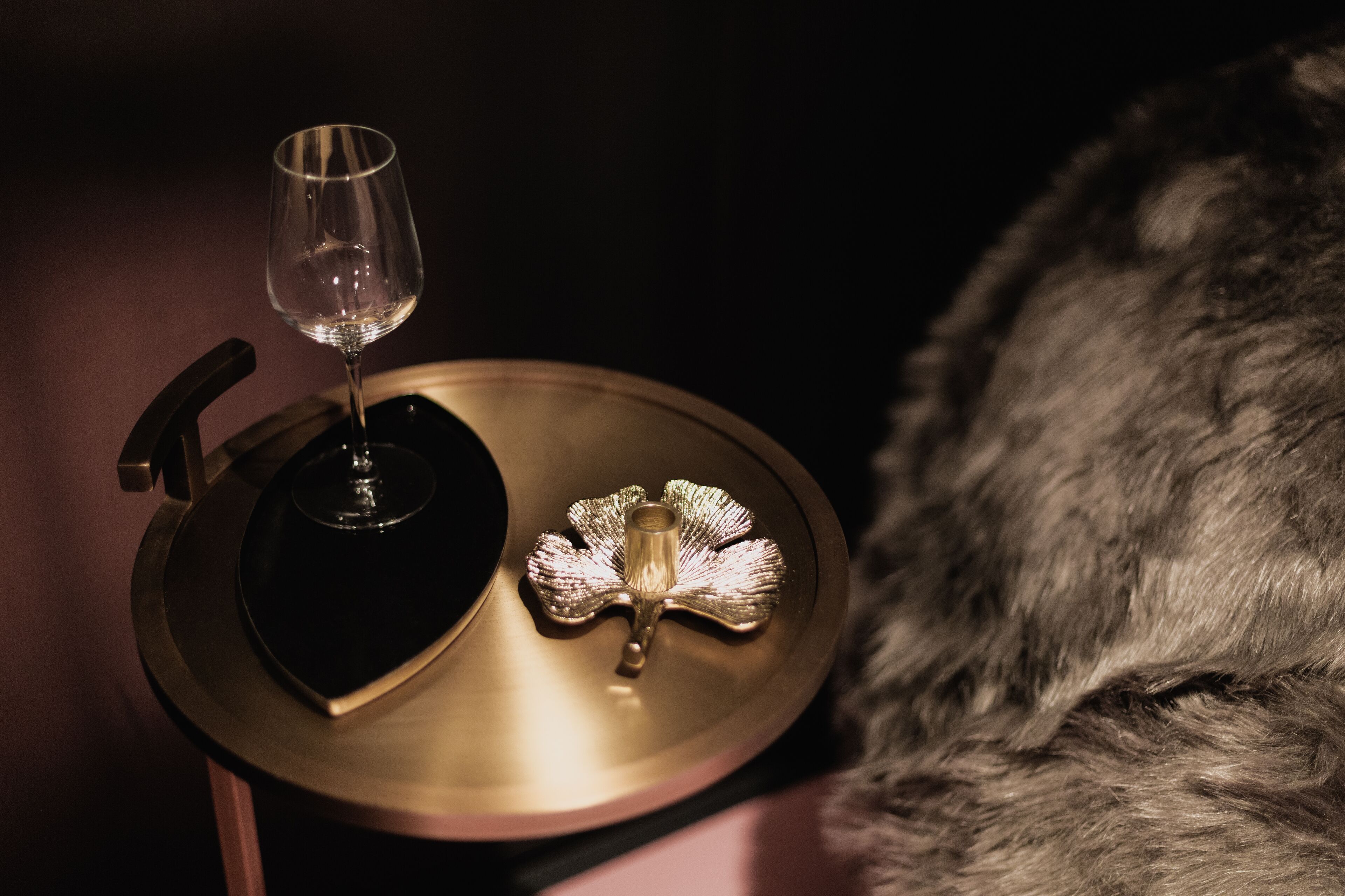 A close-up of a vinyl record player with a glass of wine and a decorative item on a table.