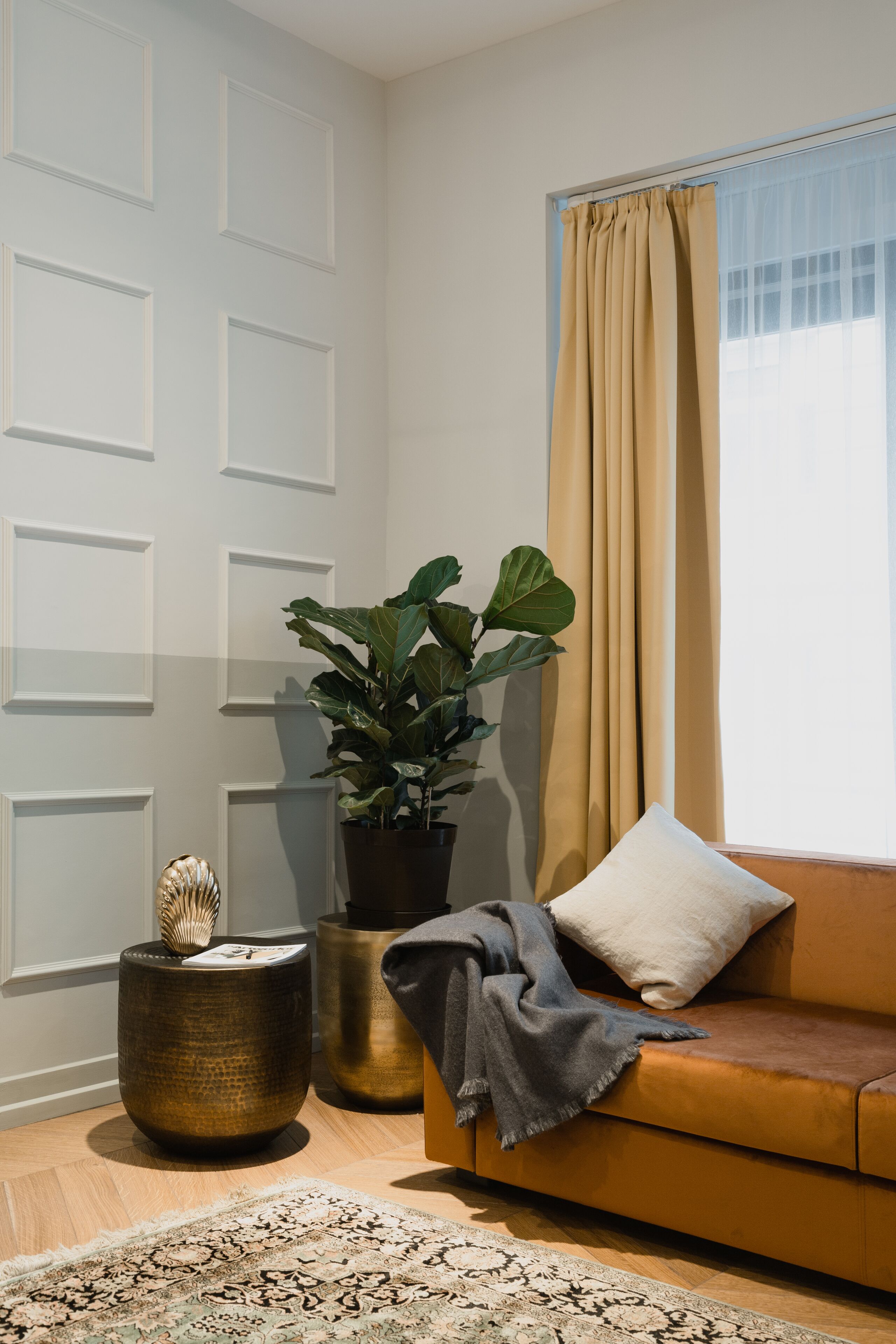 A room with a brown sofa, a potted plant, a decorative bowl, and a patterned rug.