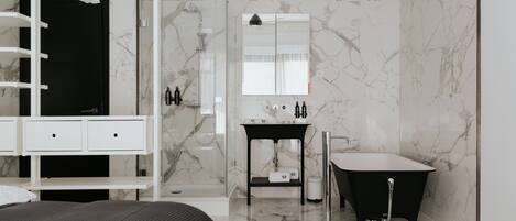 A modern bathroom with a glass shower enclosure, a black freestanding bathtub, and a vanity with a mirror.