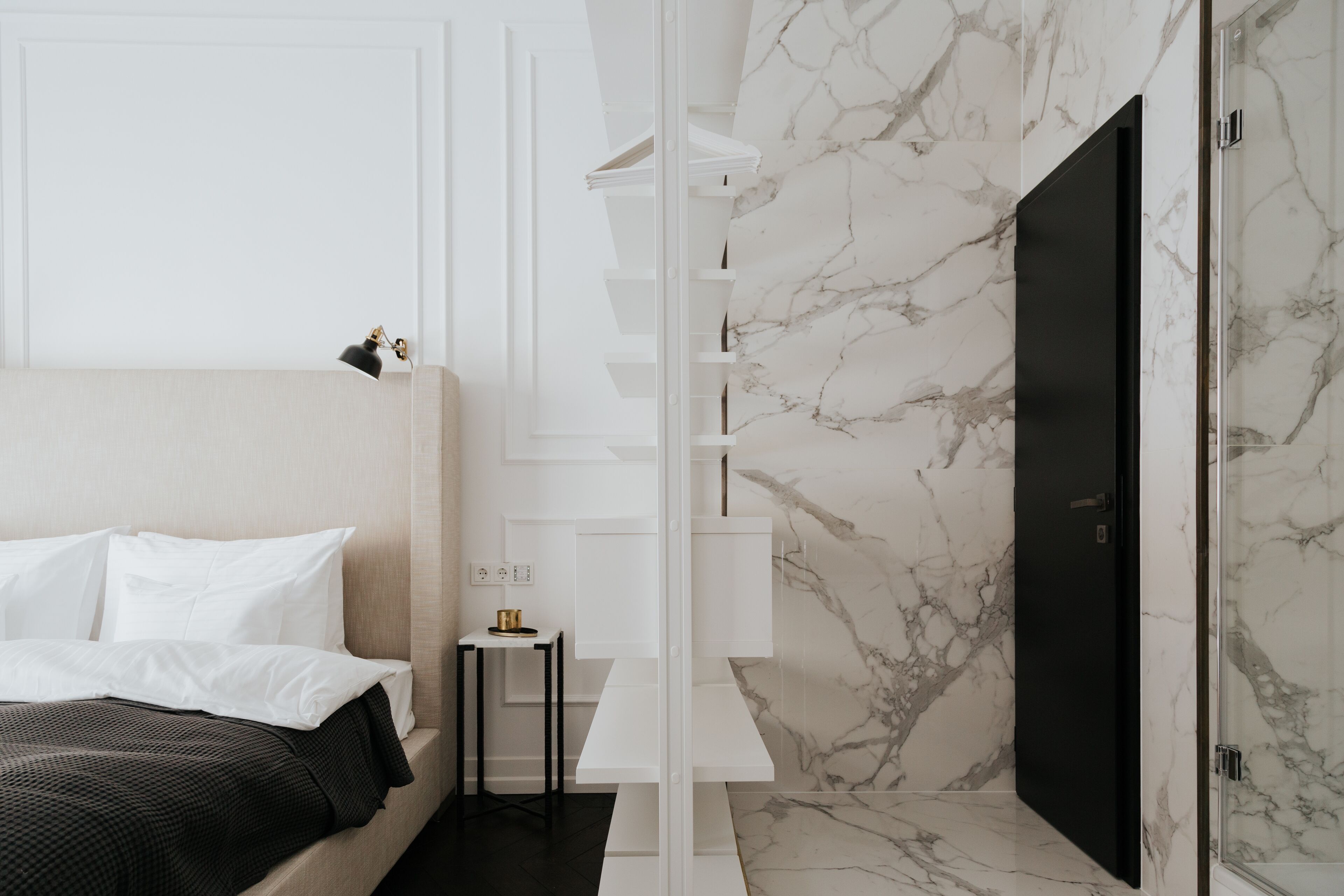 Een moderne hotelkamer met een bed, een klein tafeltje, een plankenwand en een marmeren muur.