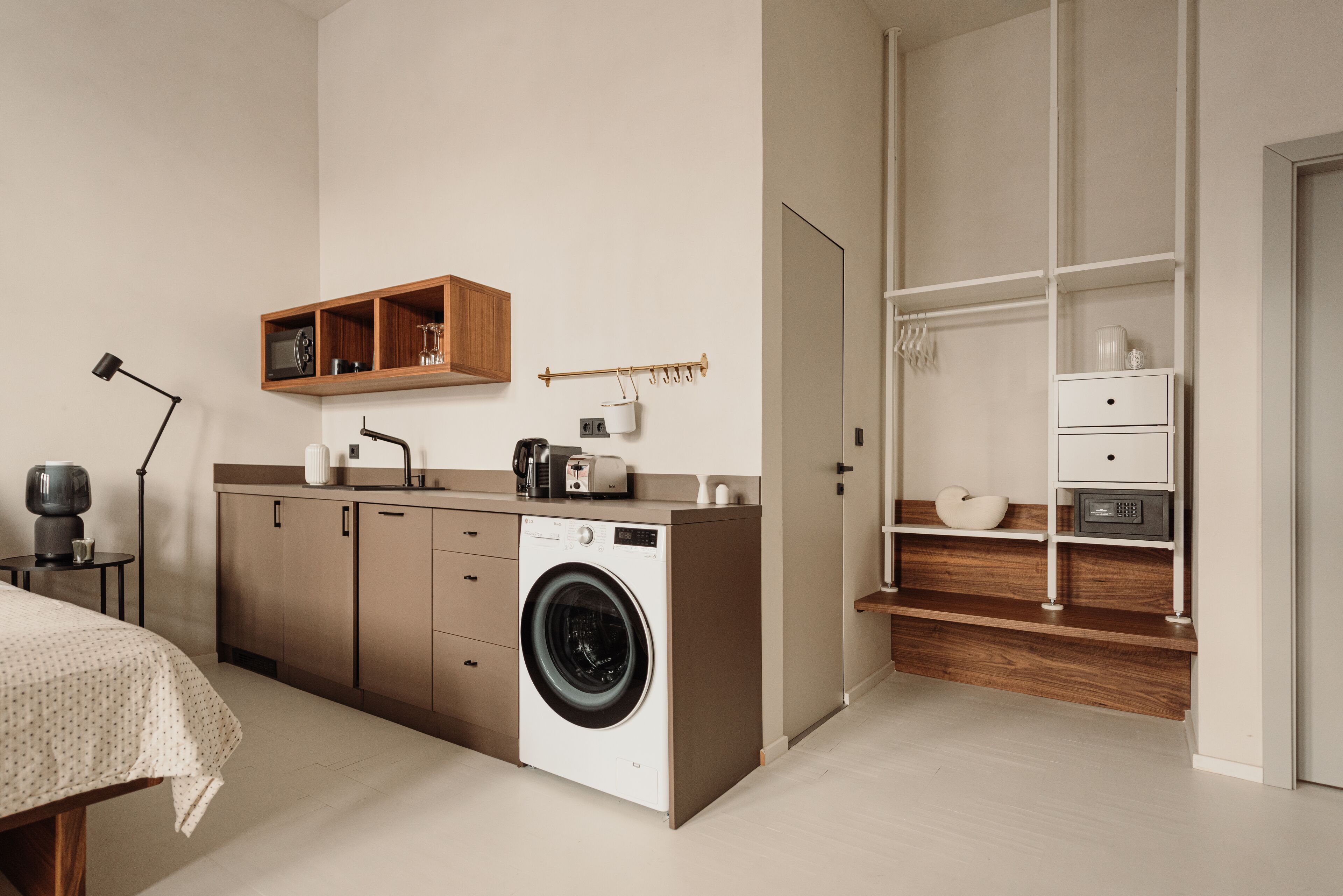 A compact kitchen with a washing machine, wooden cabinets, a microwave, and a small countertop.
