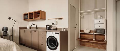 A compact kitchen with a washing machine, wooden cabinets, a microwave, and a small countertop.
