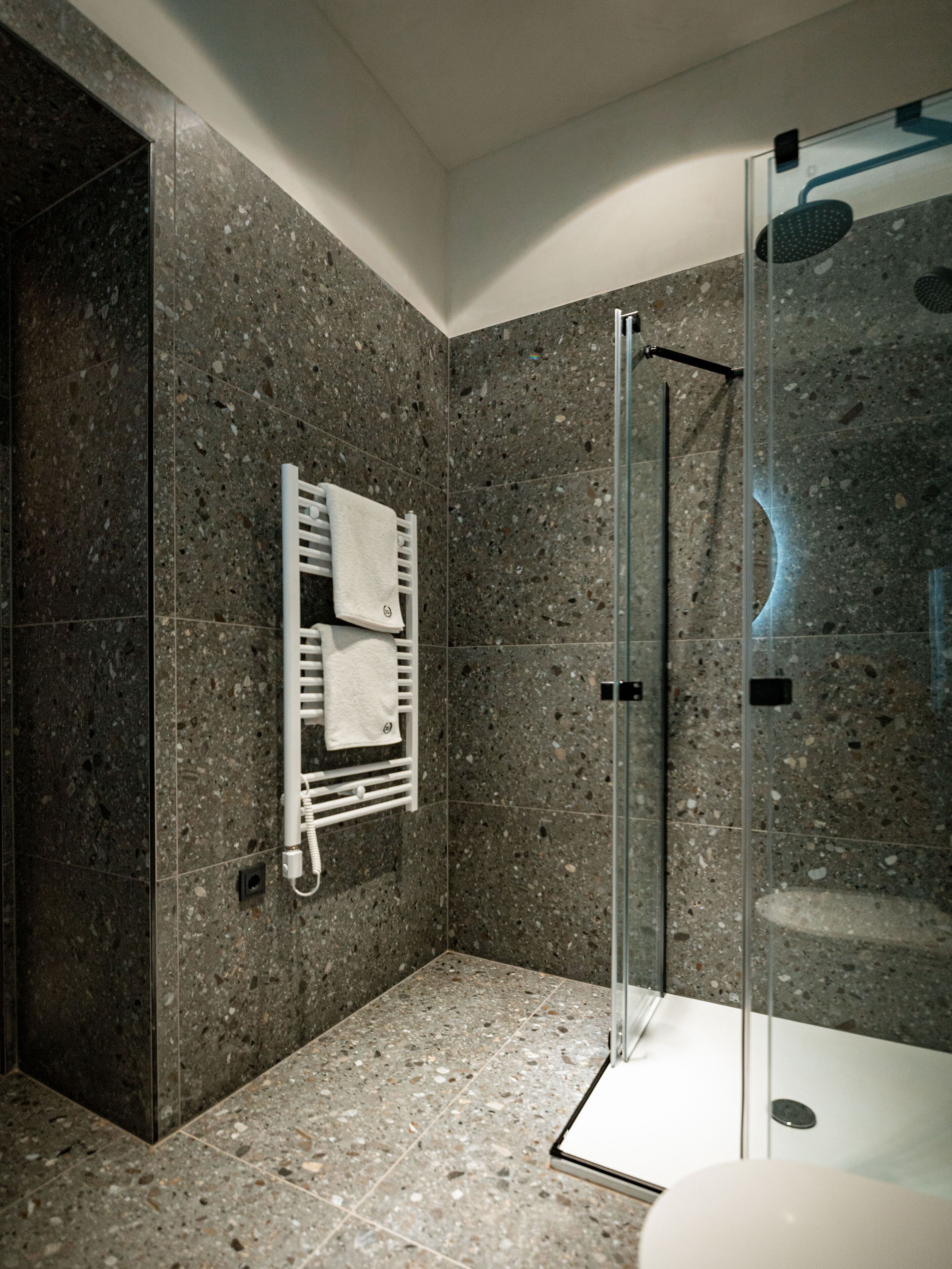 Een moderne badkamer met een douchecabine van glas, een ingebouwde handdoekhouder en een vloer van graniettegels.