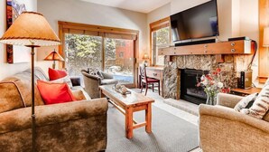 A spacious living room with a fireplace, a flat-screen TV mounted above it, and a comfortable seating area with sofas and a coffee table. - Spacious Private Condo for 6 (Keystone)