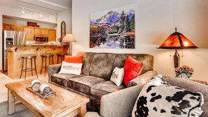 A living room with a sofa, coffee table, and a painting of a mountain landscape. - Spacious Private Condo for 6 (Keystone)