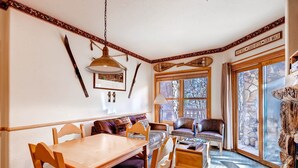 Un coin repas chaleureux avec une table et des chaises en bois, un canapé et une cheminée.