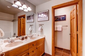 Ein Badezimmer mit Waschbecken, Holzschrank und mehreren gerahmten Bildern an der Wand.