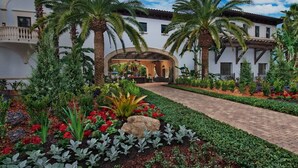 Un patio de hotel con sendero empedrado, palmeras y diversas plantas.