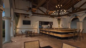 Un área de bar amplia con una isla central, diversas opciones de asientos y ventiladores de techo.