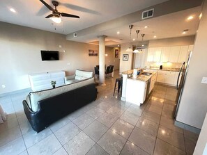 A modern kitchen with a central island, white cabinets, and a ceiling fan.