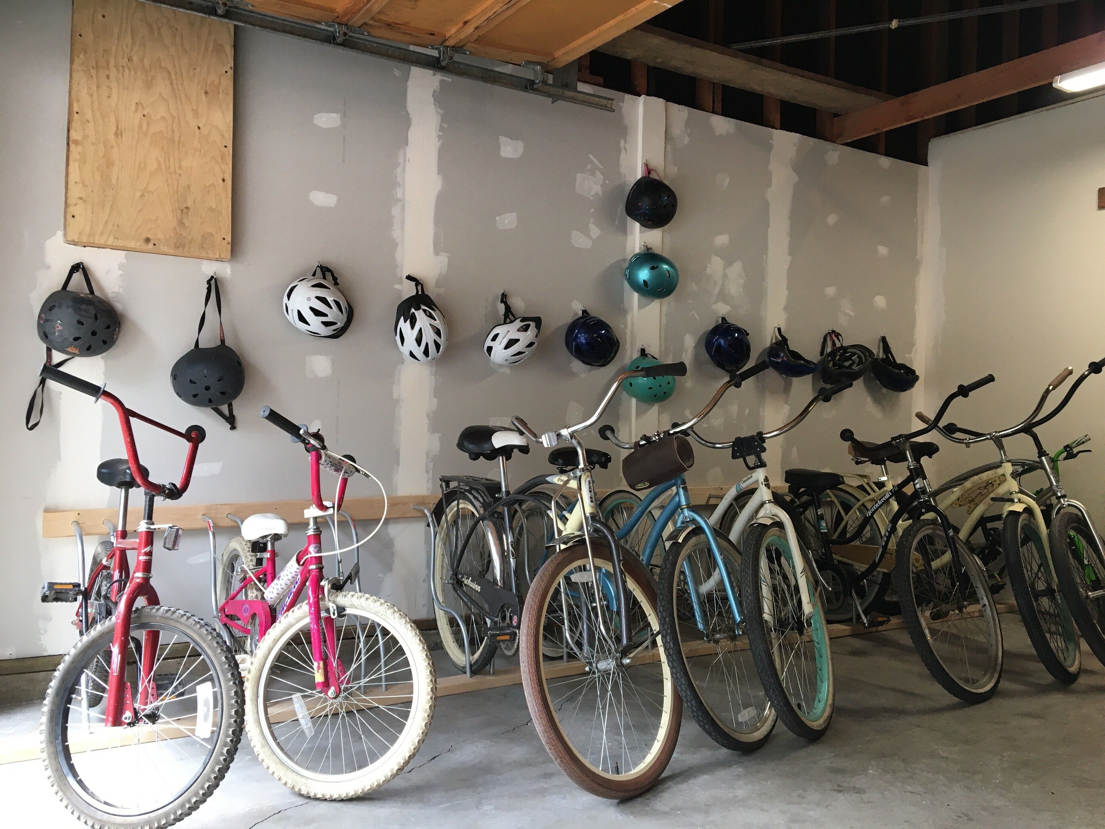 Ein Fahrradabstellraum mit mehreren Fahrrädern und Helmen an der Wand.
