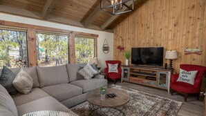 Una sala de estar acogedora con un sofá modular, una mesita de centro, un televisor de pantalla plana y un sillón rojo.