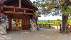 Un refugio rústico con pilares de piedra, entrada de madera y zona de estar al aire libre.