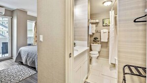 Een moderne hotelkamer met een bed, een badkamer met toilet, wastafel en douche, plus een balkon met uitzicht.