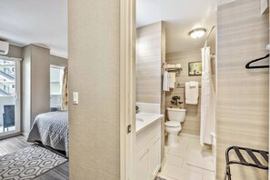 Ein modernes Hotelzimmer mit Bett, Badezimmer mit Toilette, Waschbecken und Dusche sowie ein Balkon mit Blick.