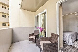 Ein Balkon mit Korbmöbeln und einem Bett in einem Zimmer.