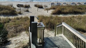 A wooden boardwalk leading to a beach with sand dunes and beach chairs. - Oceanfront Suite, Myrtle Beach SC (Myrtle Beach)