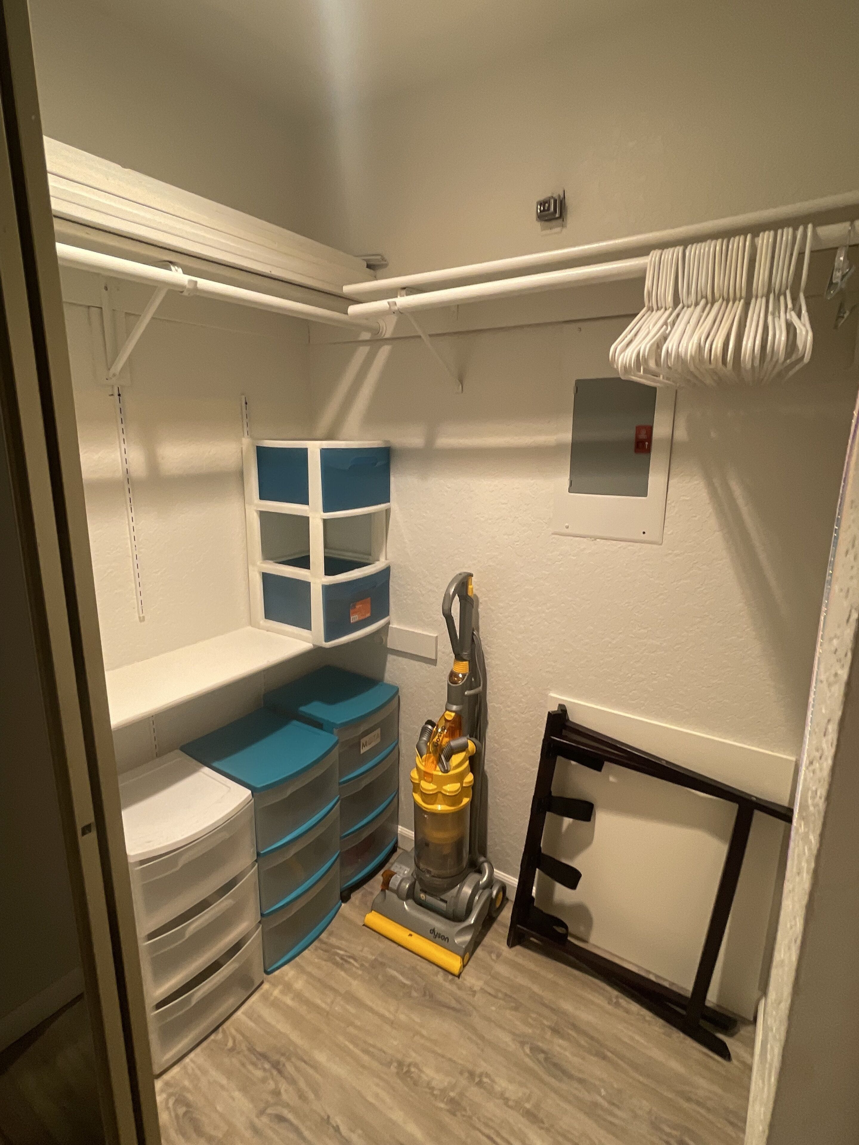A compact storage room with shelves, drawers, and a vacuum cleaner.