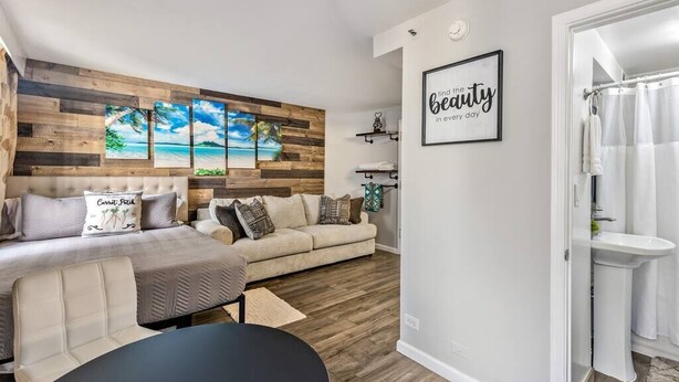 A modern living room with a wooden accent wall, a sofa, a coffee table, and a framed quote on the wall.