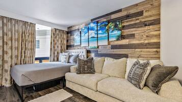 Een slaapkamer met een bed, een sofa, een houten wandpaneel en een raam met gordijnen.