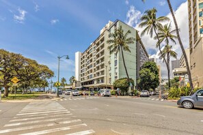 A multi-story hotel with a modern design, located at a street intersection with palm trees and a clear sky.